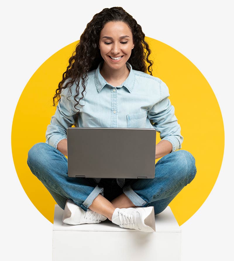 Eine Frau sitzt im Schneidersitz und schaut auf Ihr Laptop - sie freut sich über die Auswahl an CRM Branchenlösungen von awisto unddie vielen Dynamics 365 CE Referenzkunden.