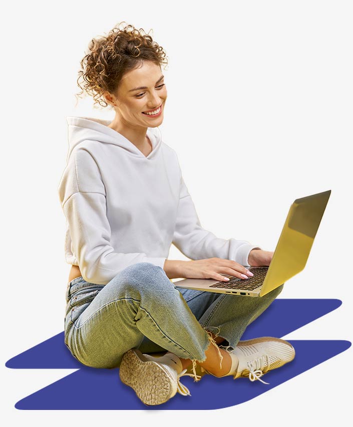 Junge Frau im Schneidersitz arbeitet am Laptop. Sie freut sich über die Portal-Integrationen mit Power Pages.